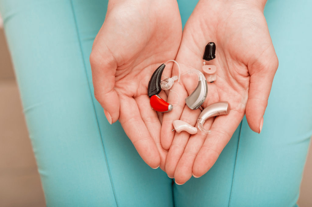 woman holding several types of hearing aids